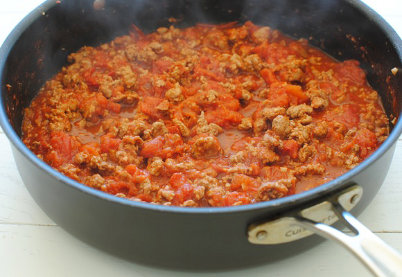Add crushed tomatoes to the browned meat.