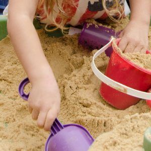 Kids play in a backyard sandbox on a hot summer day.