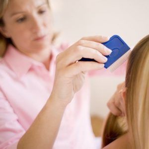 Head lice treatment. Mother combing her daughter's hair with a nit comb.