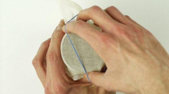 σφραγίζει με ένα χαρτί τυροκομίας το βάζο με τα φασόλια ροβίτσα