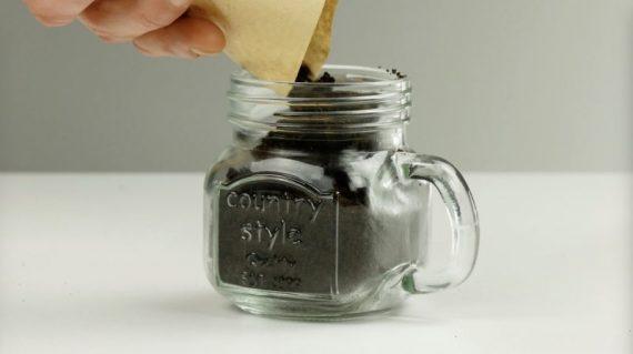 σε ένα γυάλινο ποτήρι βάζει χρησιμοποιημένους κόκκους καφέ έτσι ώστε να φυτέψει μανιτάρια