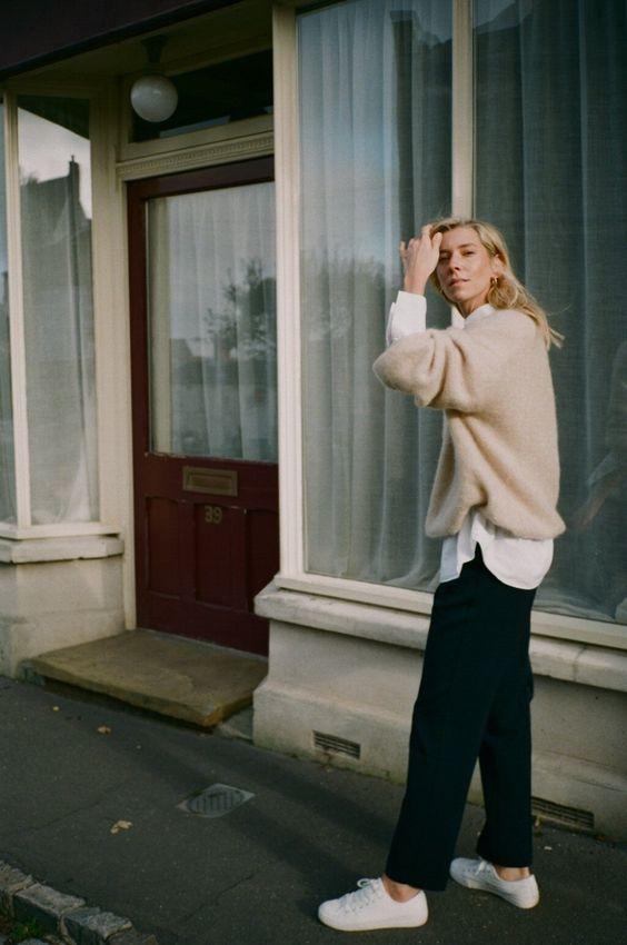 Knitwear outfit: Μπεζ πλεκτό πουλόβερ φορεμένο πάνω από λευκή μπλούζα και μαύρο jean παντελόνι 