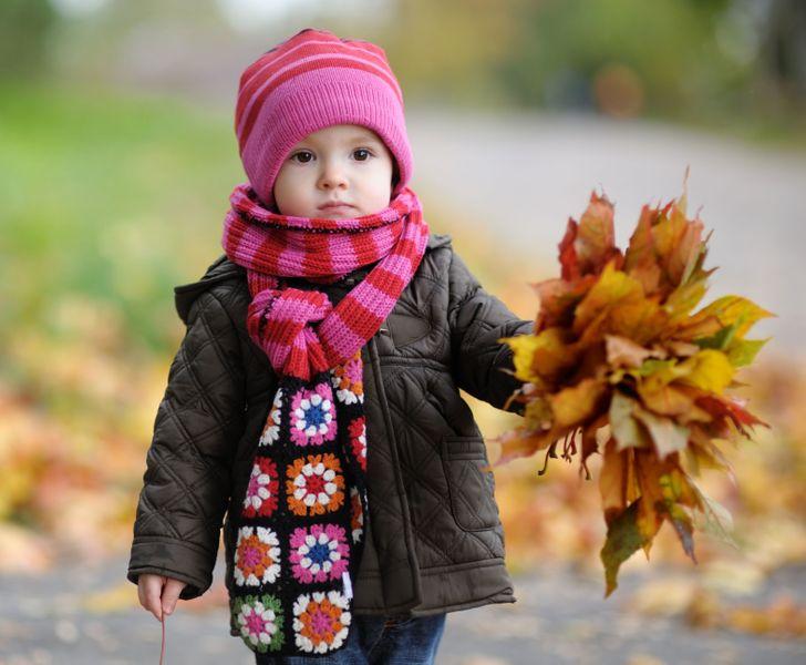 Παιδί κρατάει στα χέρια του φθινοπωρινά φύλλα 