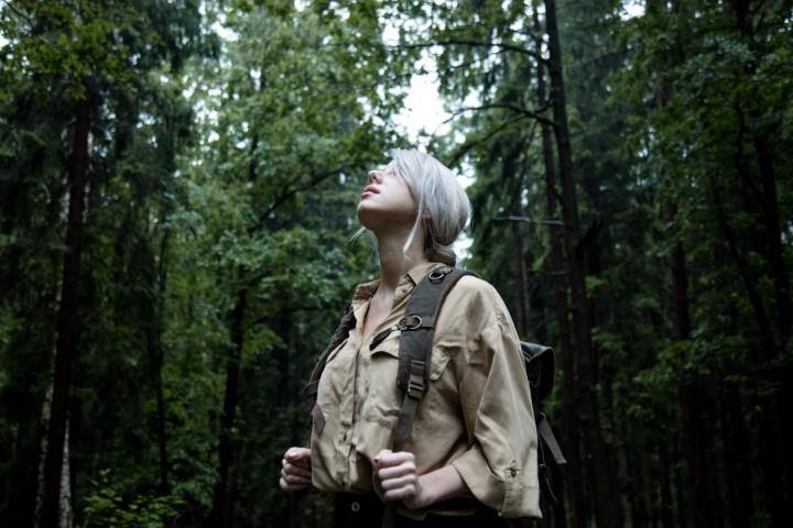 Blonde woman with backpack in rainy day in forest